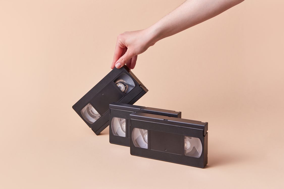 A VHS tape held beside other videotapes